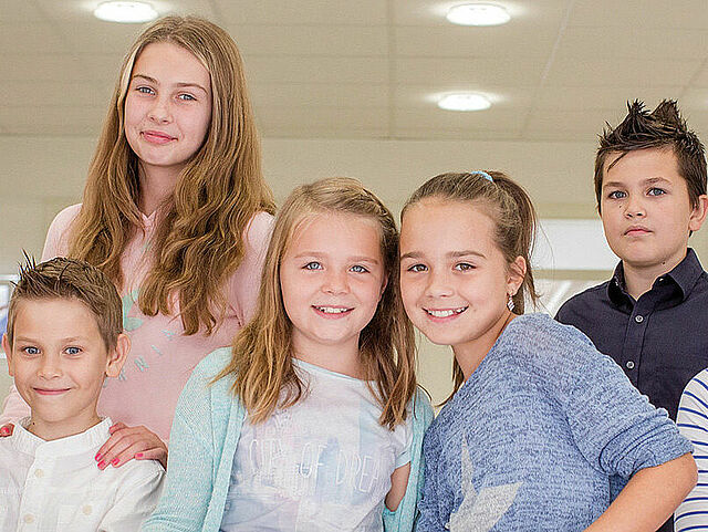 Mehrere Kinder stehen in einer Reihe und lächeln in die Kamera